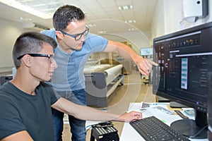 Two men wearing spectacles looking at computer screen