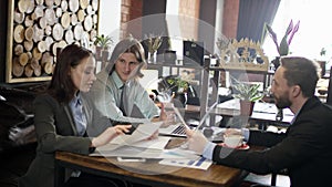 Two men and woman in business suits looking thoughtfully at documents and talking about status of reviewed project and