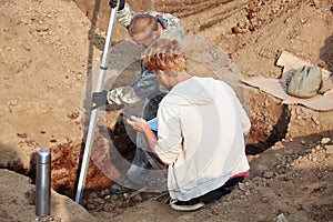 Two men at work outdoors, in digger process. Archaeological excavations.