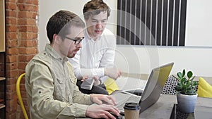 Two men working at computer sitting in business center indoors