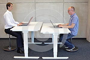Two men working in correct sitting posture on pneumatic leaning seats photo