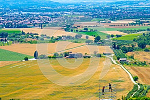 Two men are working on a scaffold, on background the italian countryside from city of Assisi, Italy, in a summer sunny day