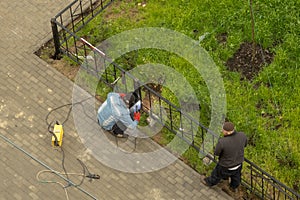 Two men working by welding build a metal fence