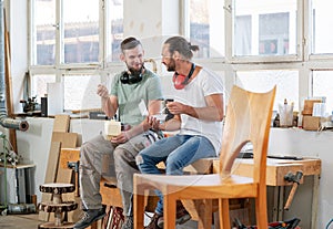 Two worker in a carpenter`s workshop taking a break