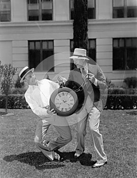 Two men wrestling with an oversized pocket watch