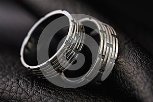 Two mens rings with different processing on a stand made of black leather