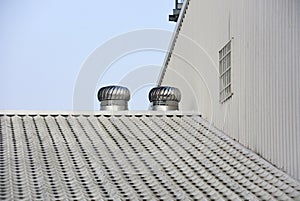 Two of metal air ventilators or air blower cooling on the metal sheet factory roof spinning take cool wind into the building