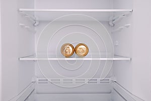 Two metal beer cans inside in empty clean refrigerator