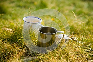 Two metal cups with tea on the mountain. Outdoors breakfast during the hike.