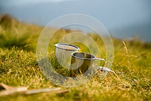 Two metal cups with tea on the mountain. Outdoors breakfast during the hike.