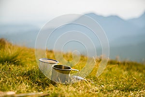 Two metal cups with tea on the mountain. Outdoors breakfast during the hike.