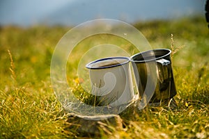 Two metal cups with tea on the mountain. Outdoors breakfast during the hike.