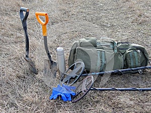 Two metal detectors shovel backpack thermos stand on dry grass photo