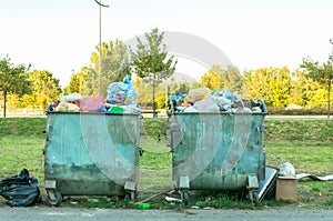 Two metal dumpster full of garbage polluting the city street.