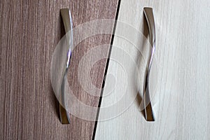 Two metal furniture handles on a brown and white door