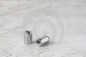 Two metal grey river nuts for hard internal thread for thin units on left part of oblong horizontal shot textured cement