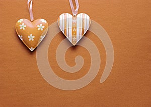 Two metal hearts in Peach Fuzz on a paper background