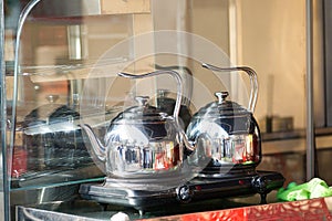 Two metal kettles in an outdoor cafe.