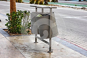 Two metal urban trash bin with garbage on tourist promenade of city