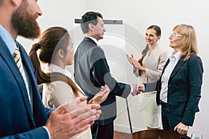 Two middle-aged business associates smiling while shaking hands