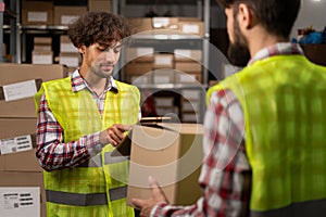 Two middle eastern warehouse workers using a digital tablet does inventory. Logistics employees working with warehouse