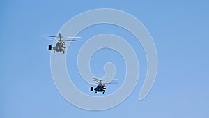 Two military helicopters flying in bright blue sky performing demonstration flight, aerobatic team