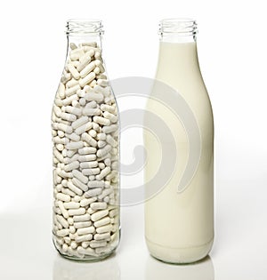 Two milk bottles one filled with milk the other filled with lactase pills