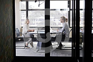 Two millennial business creatives in a meeting room for a job interview, seen through glass wall photo