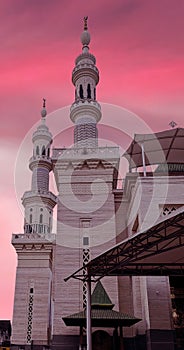 Two minarets of a mosque with a scarlett sky in the evening