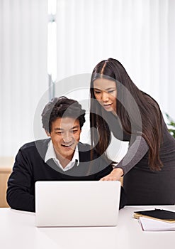 Two minds are better than one. An Asian businessman and woman having a friendly discussion while sitting in front of a