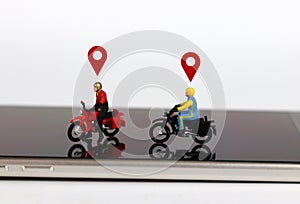 Two miniature motorcycle riders with two red location mark on the smartphone.