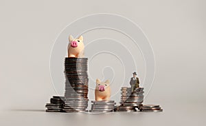 Two miniature pink piggy and a miniature man on pile of coins. The concept of capital investment.