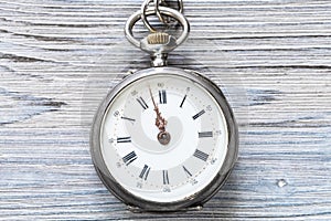 two minutes to twelve on antique watch on wood