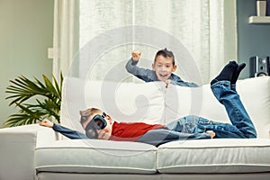 Two mischievous young brothers having fun playing on a sofa