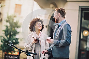 Two mixed race business people talking outside company photo