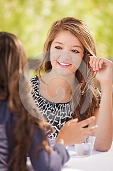 Two Mixed Race Teen Girlfriends Talking Over Drinks Outdoors