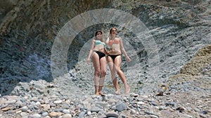 Two models in bikinis dancing on the background of rocks