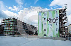 Two modern apartment block building, one with a facade scaffolding, artistically designed with a pattern of polygonal shapes,