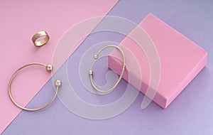 Two modern bracelets and triple shape ring on pink and purple background with copy space