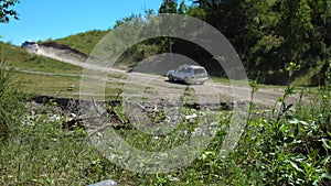 Two modern cars drive through mountainous terrain.