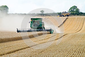 Two modern combine harvester cutting crops corn wheat barley working golden field