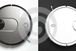 Two modern robotic vacuum cleaners on white black background flat lay. New technologies quick house cleaning automatic robot
