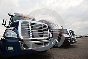 Two modern semi trucks on truck stop grills front view