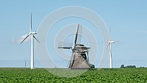 Two modern windturbines and a traditional windmill