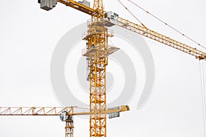 Two modern yellow construction cranes above sky