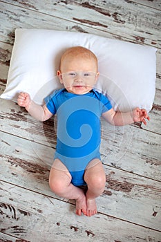 A two-month-old baby lies on the floor