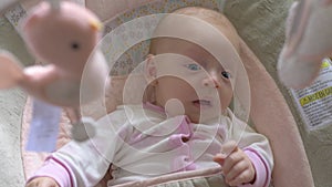 Two months old baby girl under the baby mobile