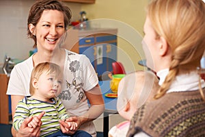 Two Mothers With Children Chatting At Playgroup