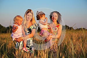 Two mothers with children on wheaten field