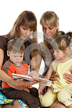 Two mothers read books to their children